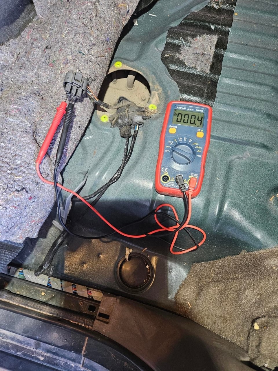 Checking voltage at the fuel pump connector with a multimeter, indicating a lack of power supply.