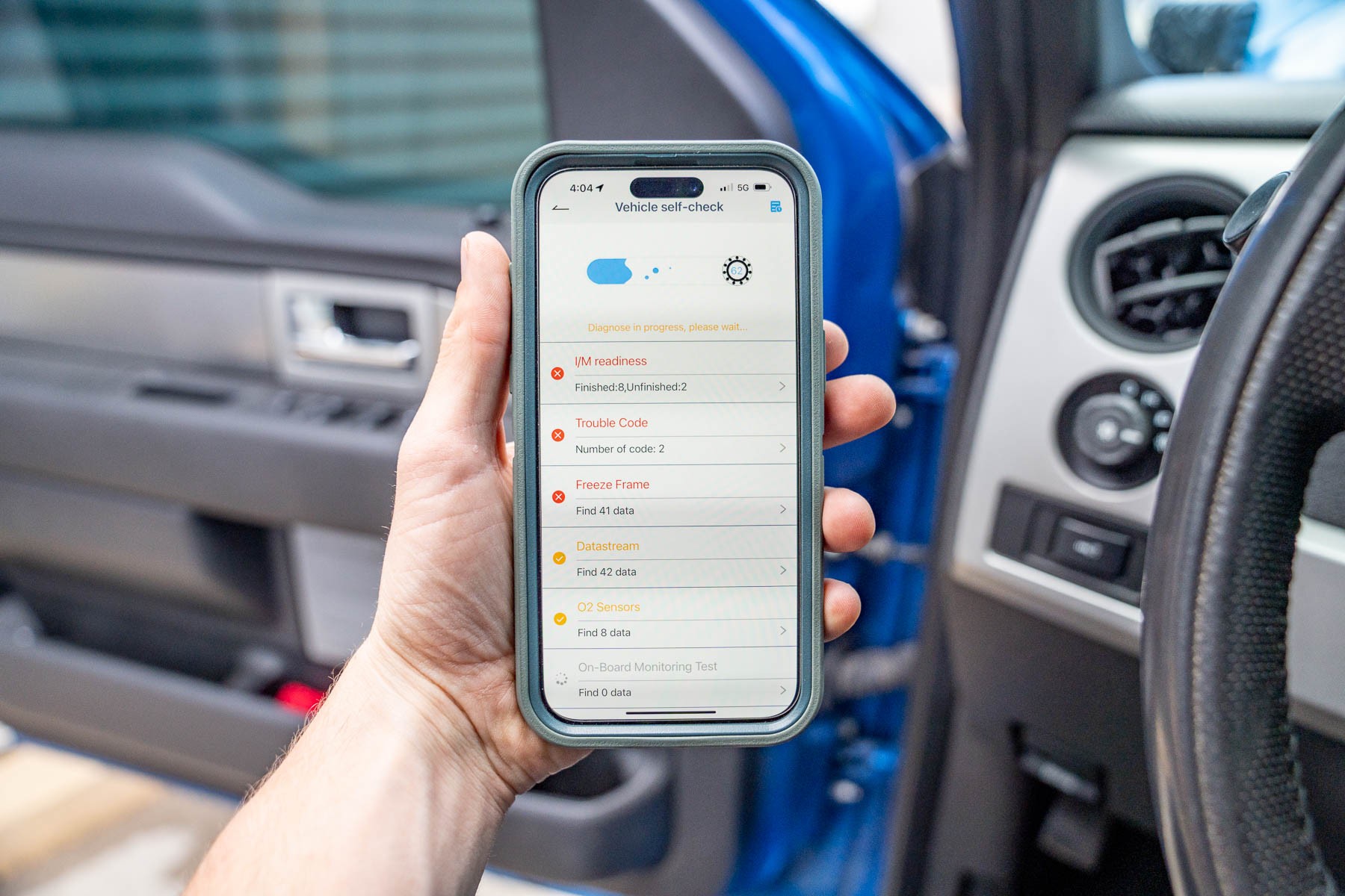 Driver using a Bluetooth OBD2 scanner app on a smartphone