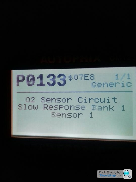 Aston Martin V8 Vantage dashboard displaying an emissions service warning error code, diagnosed using an OBD2 port.