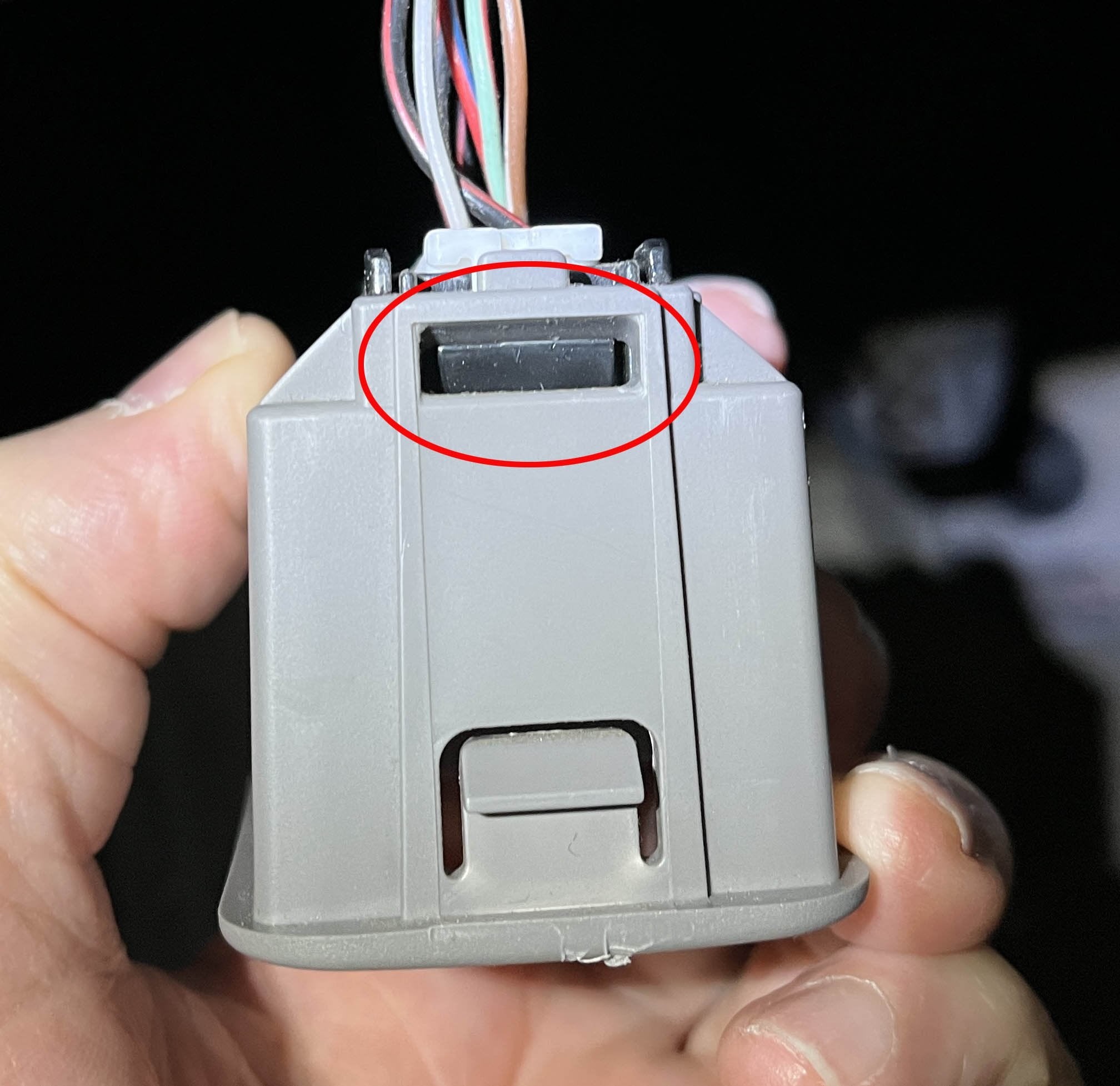 Close-up view highlighting the locking tabs on the OBD2 port housing of a 2017 Subaru WRX, crucial for removal.