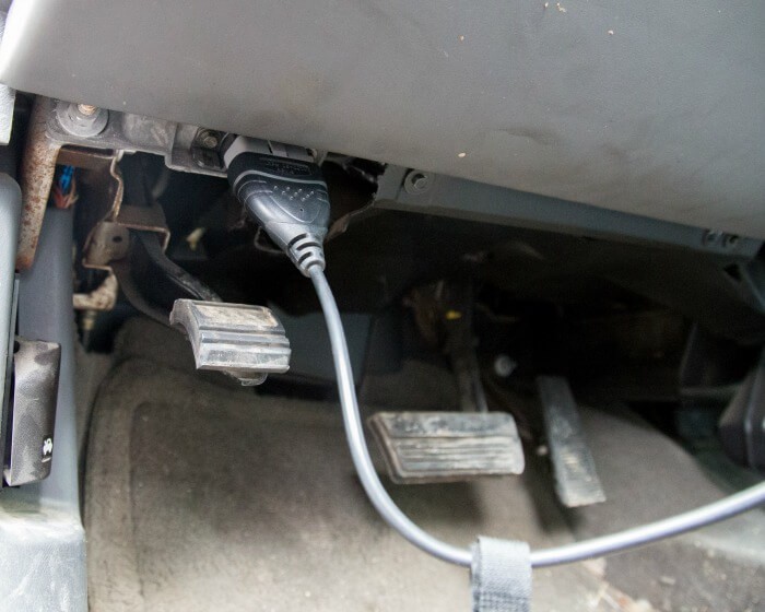 Connecting an OBD2 scanner to the diagnostic port located beneath the steering wheel for quick vehicle health checks.