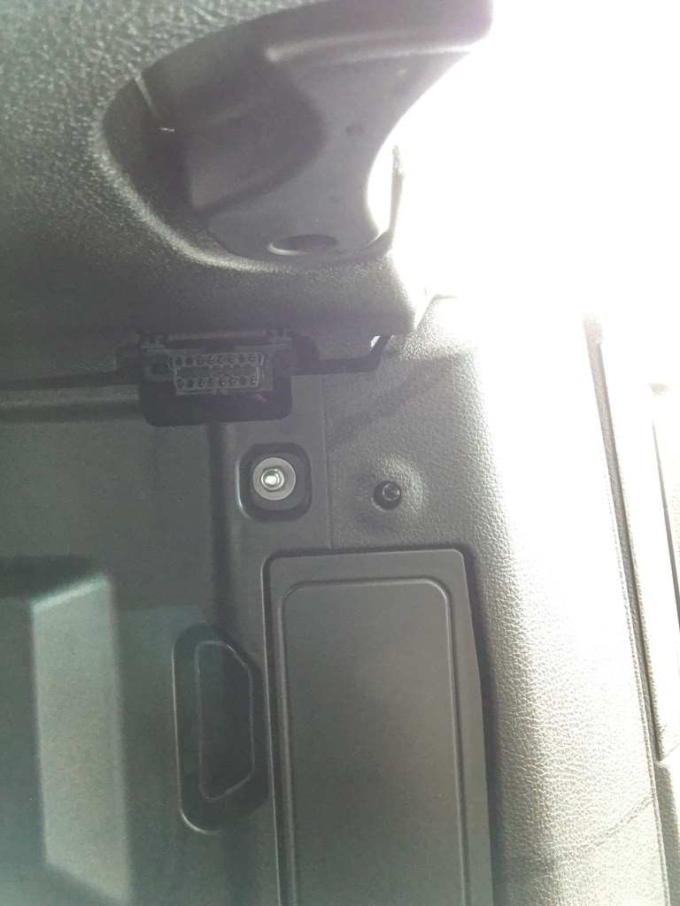 Trapezoidal OBD2 port in a car, highlighting its standard shape and accessibility for diagnostic tools